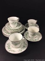 View of all 16 pieces in the set, including cups, saucers, and plates, arranged showing the floral pattern and platinum rim.
