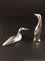 Two signed Hoselton metal bird sculptures, a loon and a penguin, displayed against a black background.