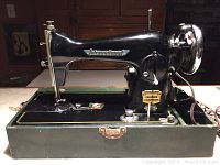 Front right angle view showing International logo on the arm and machine base with attached components and chrome handwheel.