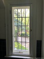 Full view of original leaded glass window installed with white frame and multiple small panes.