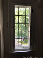 Full view of the tall leaded glass window showing multiple panes, white frame, and interior screen.