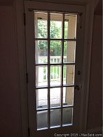 Full view of white wooden French style door with fifteen glass panes in a 3x5 layout, showing the door installed with an exterior deck visible through glass.
