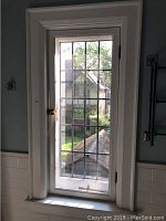 Full view of the original leaded glass window installed in an interior wall, showing the leaded glass pattern and white wooden frame.