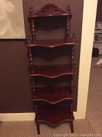 Full view of the five-tier wooden shelf showing turned supports and carved decoration.