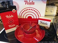Set shows red ceramic party bowl with central hole for melting dish, electric warmer underneath, four red-handled fondue forks inside melting dish, original Velata box and instruction booklet