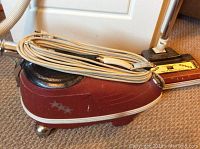 Side view of maroon Tri Star canister vacuum with power head and attached wrapped cord.