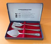 Cheesemaster boxed set with three silver plated cheese serving utensils arranged inside open blue box with descriptive white satin lid liner.