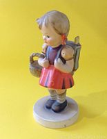 Front and side view of handpainted HUMMEL figurine of young girl holding a basket with a backpack, standing on a round base against a yellow background.