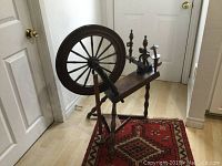 Full view of antique wooden spinning wheel with large wheel and spindle assembly on plank base