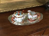 View of complete set with creamer and sugar bowl on silver plate tray.