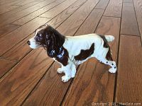 Side profile of the Goebel spaniel figurine on a wood floor to show length and detail