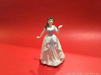 Full view of the Royal Doulton figurine with a red background, showing the complete figure in a flowing dress.