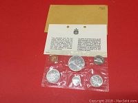 Photo of entire lot including all six coins sealed in plastic holder with attached information card and brown folder above.