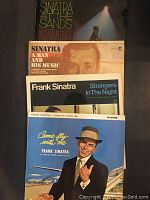 Four vinyl records stacked showing album covers with Frank Sinatra titles: At The Sands, A Man and His Music, Strangers In The Night, and Come Fly With Me.