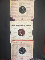 Three vintage 78 RPM records in their original paper sleeves, arranged vertically. The top record is in a Columbia sleeve featuring purple and white color with musicians illustrated. The middle and bottom records are His Master's Voice with a diamond pattern and red trim.