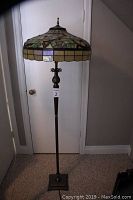 Full view of lamp showing stained glass shade, metal column, and square base