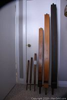 Photo showing all six wooden organ pipes of varying lengths and colors, standing vertically against a wall, from approximately 24 to 68 inches.