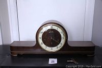 Full front view of Junghans wooden mantle clock with winding key beside it
