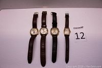 Four Bulova watches laid flat showing watch faces and leather straps in dark brown and black colors.