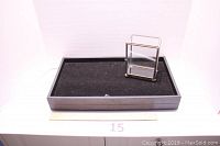 Photo showing one black velvet-lined rectangular stacking jewelry display tray and the small square glass jewelry display box with metal frame placed inside it.