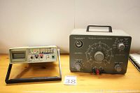 Fluke 8050A digital multimeter and Heathkit condenser checker side by side on a wooden surface.