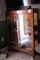 Front and side view of wooden display cabinet with glass doors and shelves