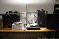 Various miscellaneous electronic items arranged on a table including a black amplifier, white antenna, manuals, and other items.