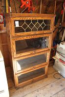 Front view of full bookcase showing four stacked glass-front sections and leaded glass top door
