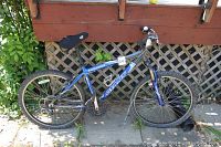 Full side view of the blue Boulder SE mountain bike by Giant showing frame, tires, seat and handlebars.