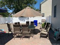 Full overview of glass top table, ten chairs, umbrella and stand on patio
