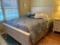 Assembled bed with headboard, footboard and bedding in room setting