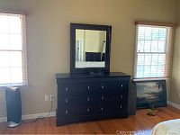 Full view of dark wood dresser with matching mirror in room setting.
