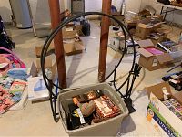 Photo showing the metal frame log holder with an arch handle, plastic storage bin holding several boxes of fire starters and other items.