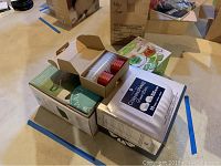 Overview photo of boxed kitchen items including CorningWare French White, Martha Stewart packaging, and storage containers.