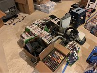 Multiple items laid out on floor: Xbox 360 console, controllers, games, power supplies and accessories.