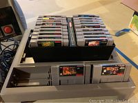 SNES console with black plastic case holding game cartridges