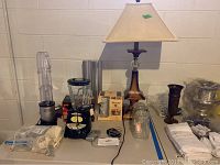 Full view of lot showing lamp, kitchen appliances including Hamilton Beach blender, Magic Bullet, chef's Choice knife sharpener, two apothecary jars, Yuengling beer glasses boxed.