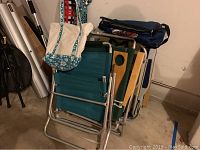 Four folded beach chairs stacked together, showing metal frames and fabric seats.