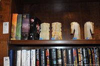 Photo showing four carved marble bookends and four hardback books on a wooden shelf.