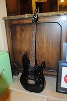 Full body view of black Ibanez electric guitar showing double cutaway design and glossy finish.