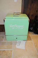 Front view of mint green Dr. Pepper cooler with logo and chrome handle on the lid.