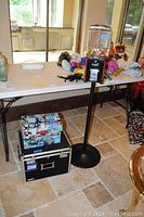 Photo showing the gumball machine on black metal stand with colorful gumballs, and the two boxes on the floor beside it