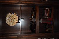 Wide shot of wooden cabinet shelf showing decorative plate on stand, carved wood turtle and rabbit boxes, and wooden treasure chests