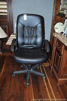 Front view of black leather IKEA office chair showing sized approximately 26x26 with visible wear on seat cushion.