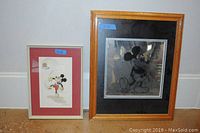 Two framed Mickey Mouse artworks side by side, one smaller with red mat framing colored drawing, the other larger with black mat framing black and white drawing.