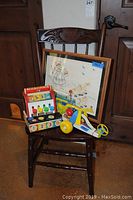 Vintage Fisher Price wooden toys and framed needlepoint displayed on carved wooden chair