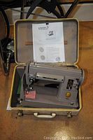 Singer Model 301 sewing machine in its original hard-shell case with instruction manual visible inside the lid.