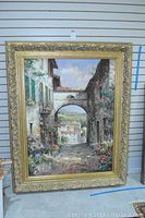 Full view of the large framed oil painting showing detailed street scene with flowers and an archway.