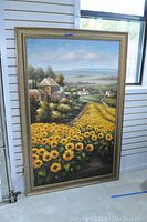 Full view of the large framed painting showing the sunflower field and village scenery