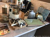 Photo of all kitchen appliances and knife block arranged on counter including Philips food processor, Hamilton Beach toaster, warming tray, knife block with steak knives, and Imperial blender.